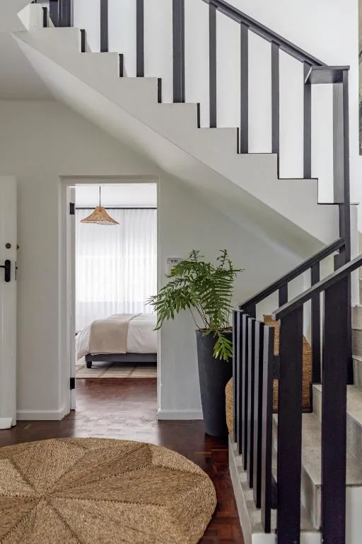 Modern staircase with black metal railings and woven round rug below
