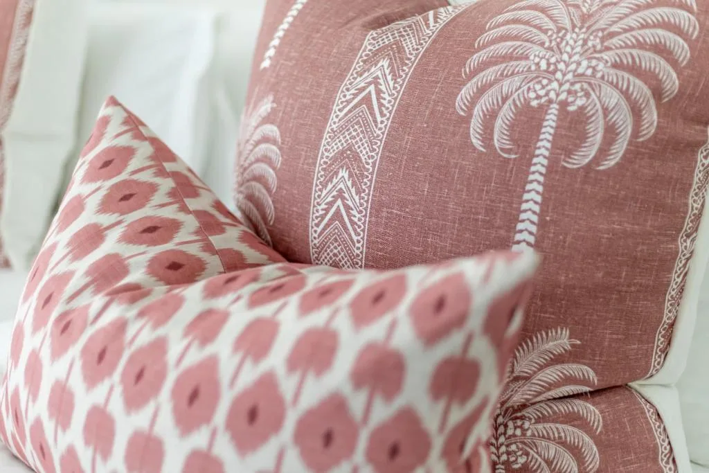 Close-up of decorative cushions with pink geometric and palm tree patterns