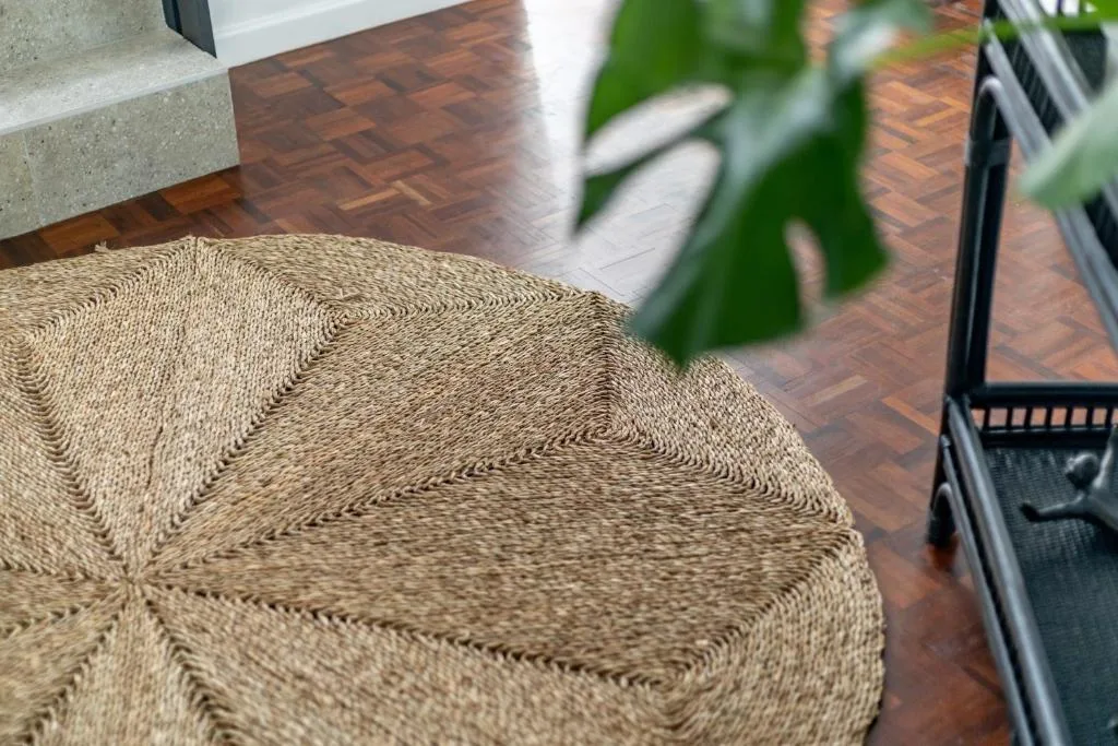 Close-up of woven circular rug on herringbone wooden floor with potted plant