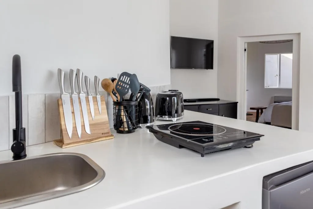 Modern kitchen counter with knife set, portable cooktop, and appliances