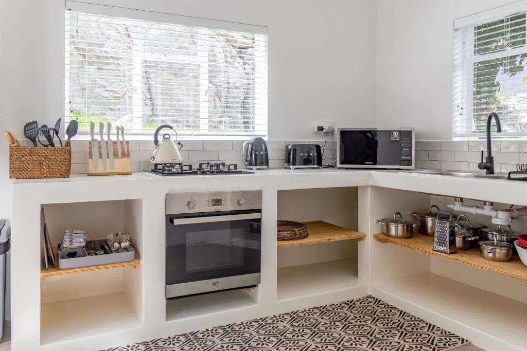 Modern kitchen with white cabinetry, stainless steel oven, and countertop appliances