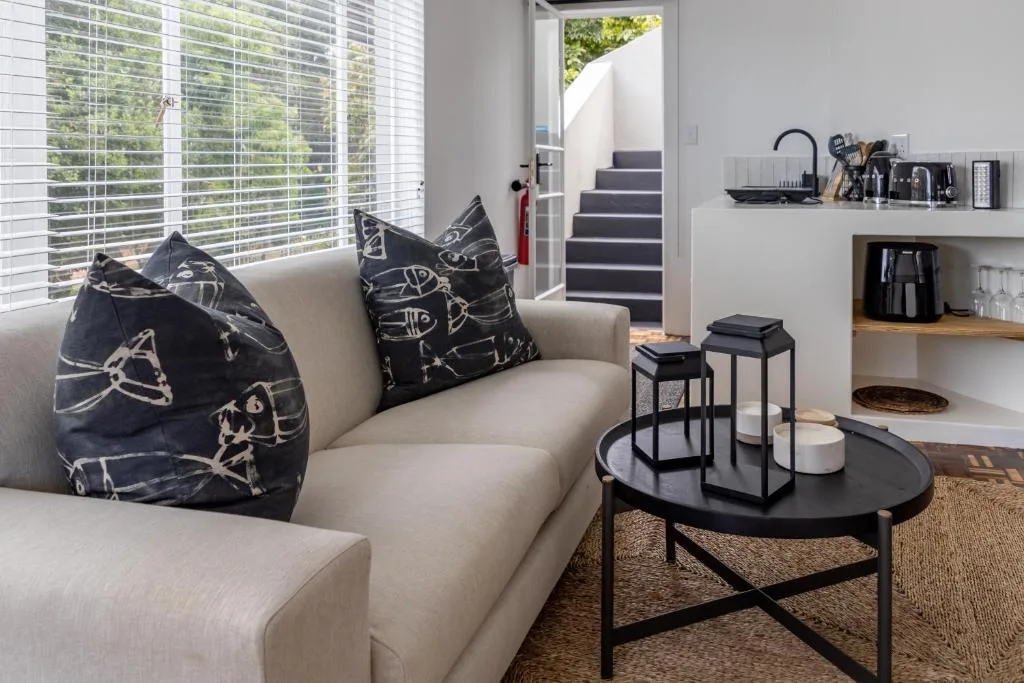 Modern living room with beige sofa, patterned pillows, and black coffee table