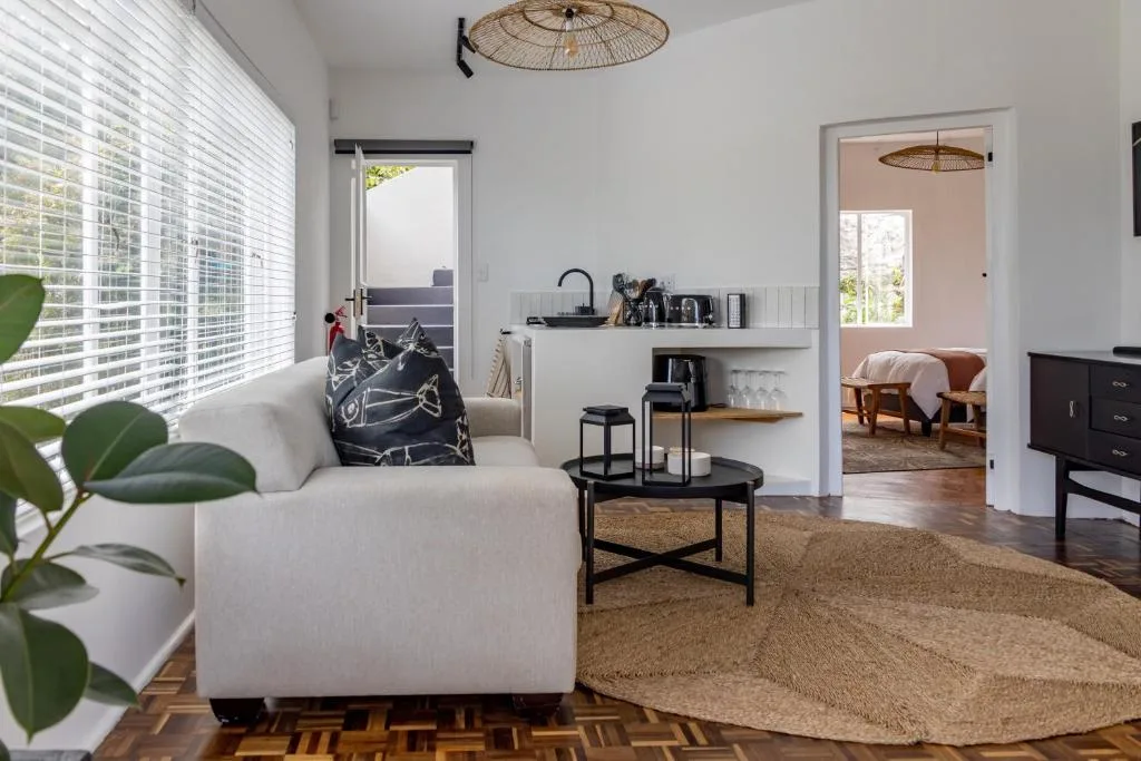 Bright modern lounge with cream sofa, woven pendant light, and ocean view doors