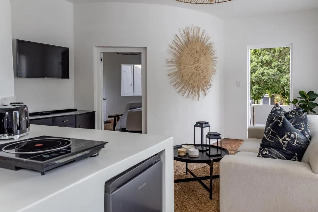 Modern lounge with cream sofa, wall-mounted TV, and natural light from glass doors