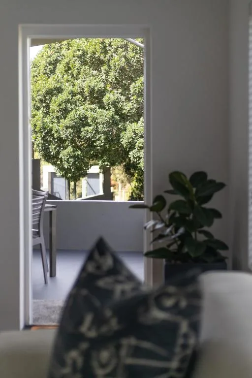 Lush green trees visible through open glass doors and windows