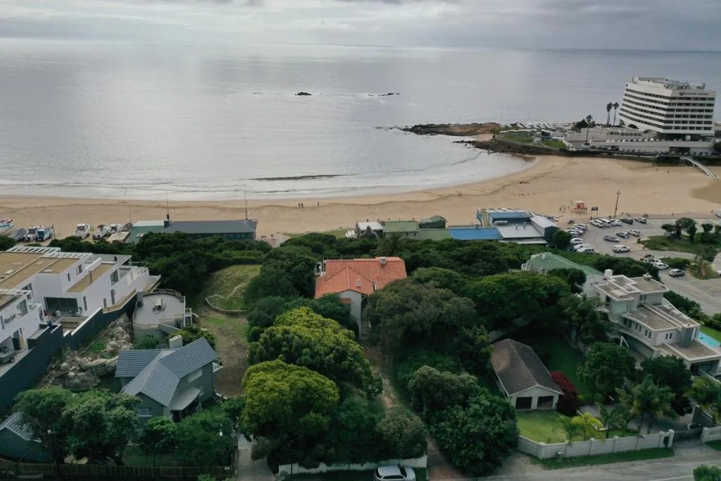 Aerial view of beachfront property with sandy bay and ocean beyond