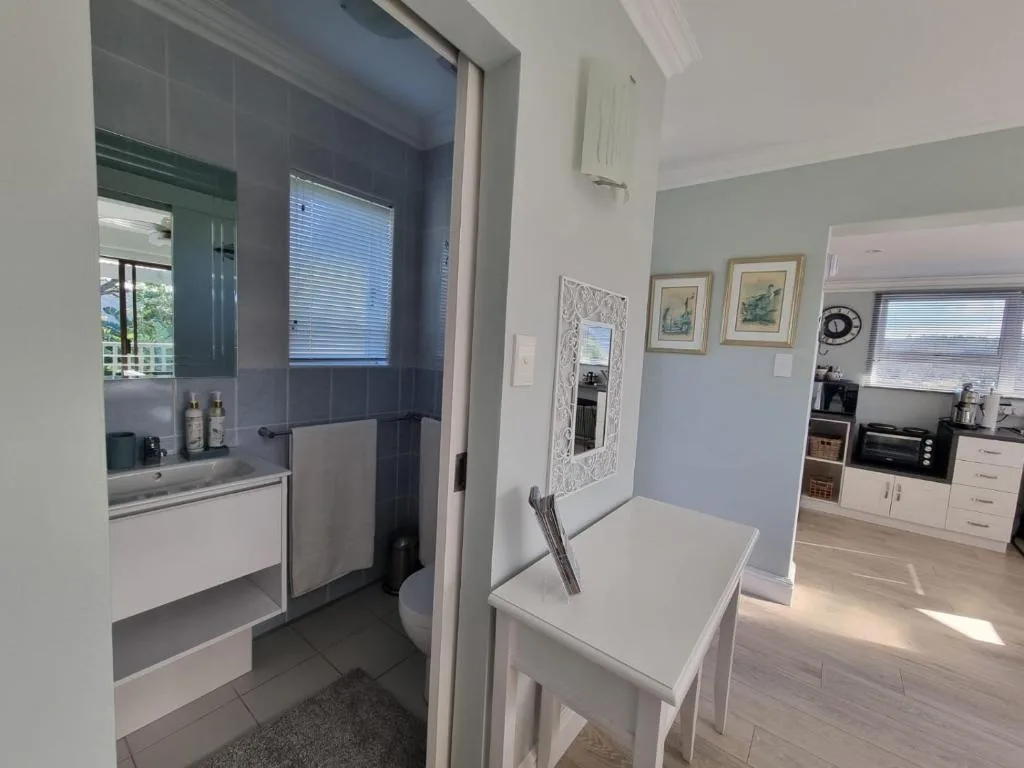 Modern bathroom with vanity, shower enclosure, and window with blinds