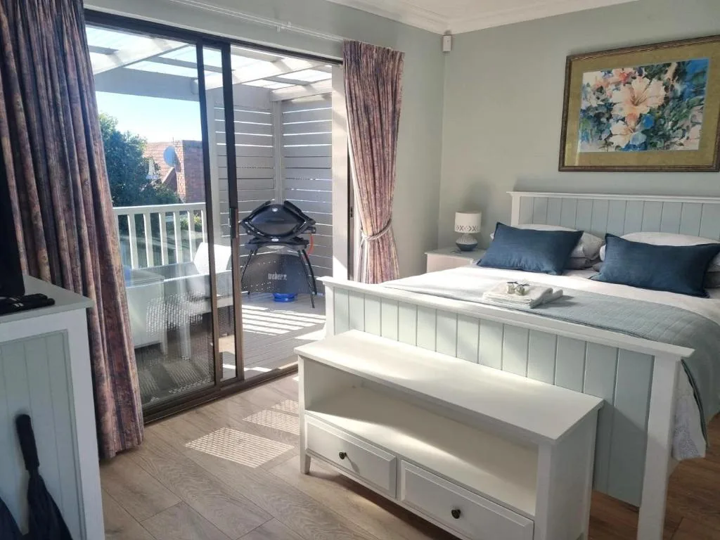 Bright bedroom with queen bed, white headboard, and private deck access