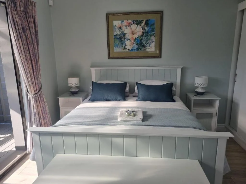 Bright modern bedroom with white bed frame and navy pillows, bedside lamps