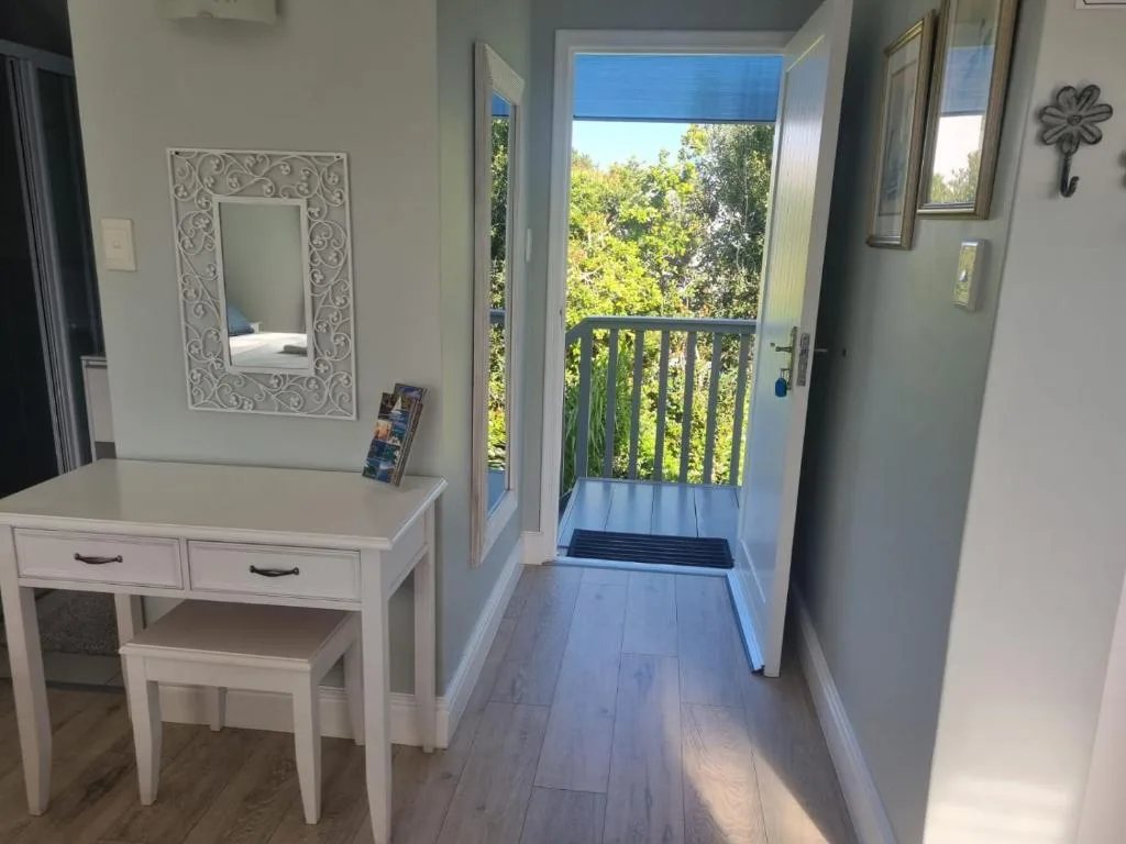 Bright bedroom with vanity desk, ornate mirror, and door to green treed deck