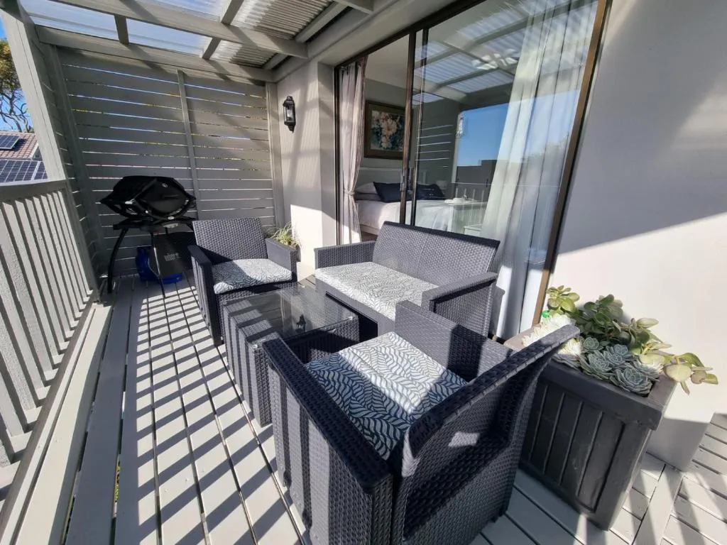 Covered patio with rattan furniture, braai grill, and indoor access