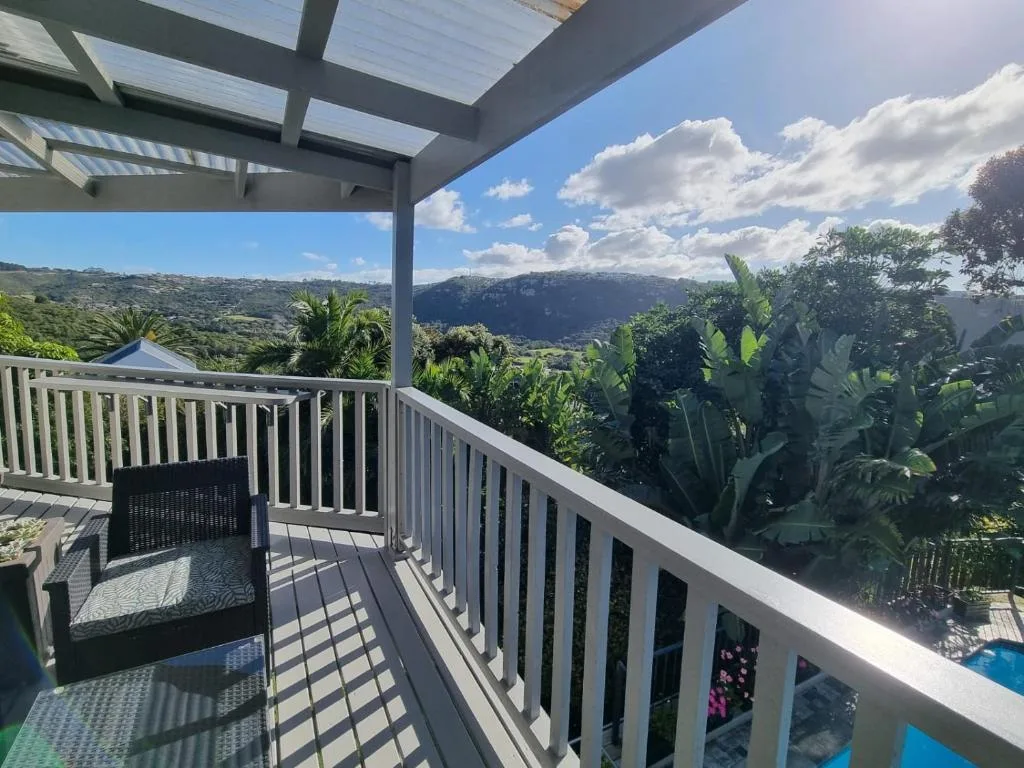 Covered deck with white railings overlooking lush valley and mountains