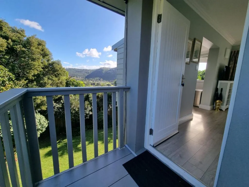 Modern deck with railing overlooking lush garden and mountain vista