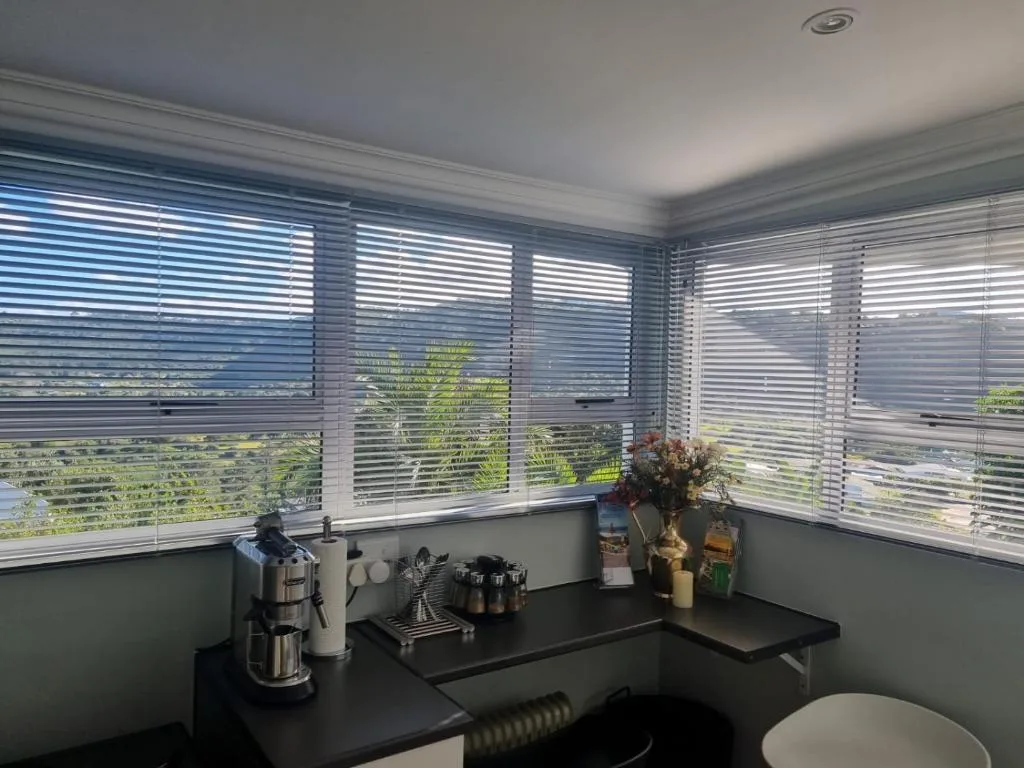 Modern kitchen counter with coffee maker and amenities near large windows