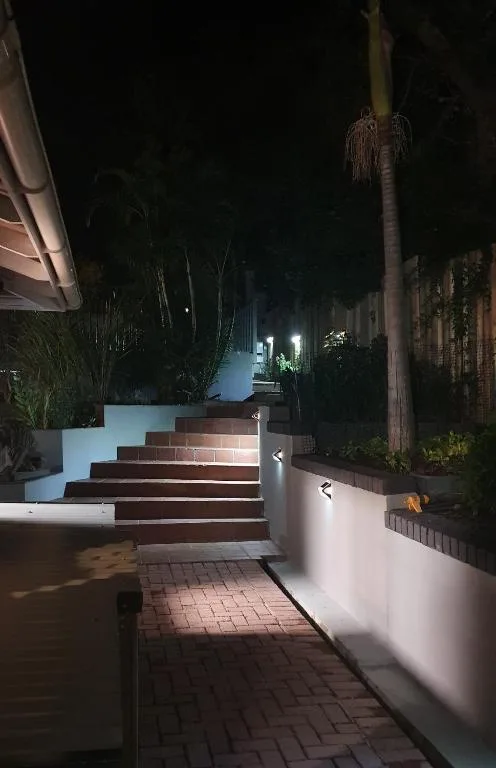 Nighttime entrance with brick steps, white walls, and palm trees