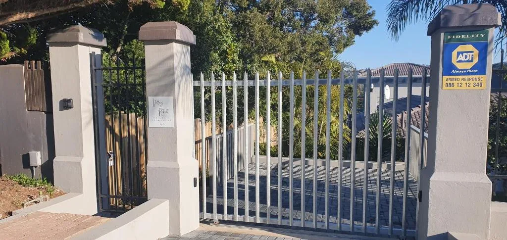 Gated entrance with white pillars and metal security gate to property