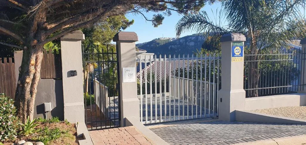 Gated entrance with white pillars and mountain views beyond gates