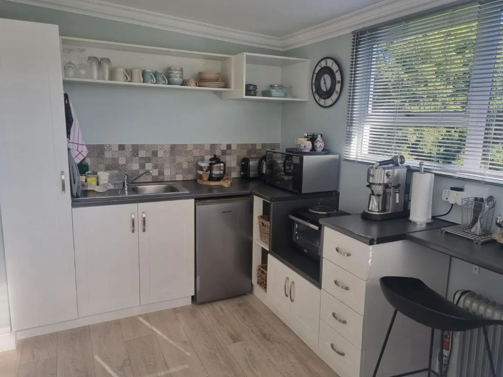Well-equipped kitchen with white cabinetry, black countertops, and modern appliances