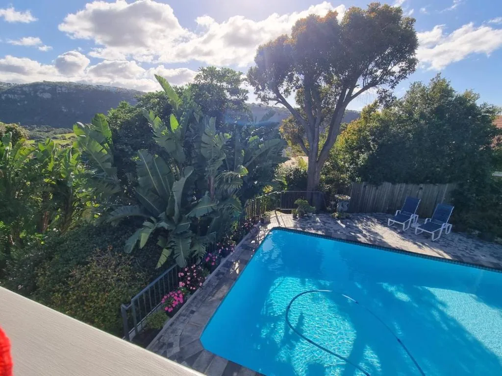 Sparkling blue swimming pool surrounded by lush gardens and mountain views
