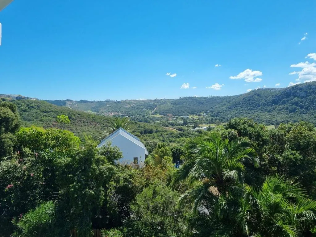 Lush green valley landscape with distant mountains and blue sky