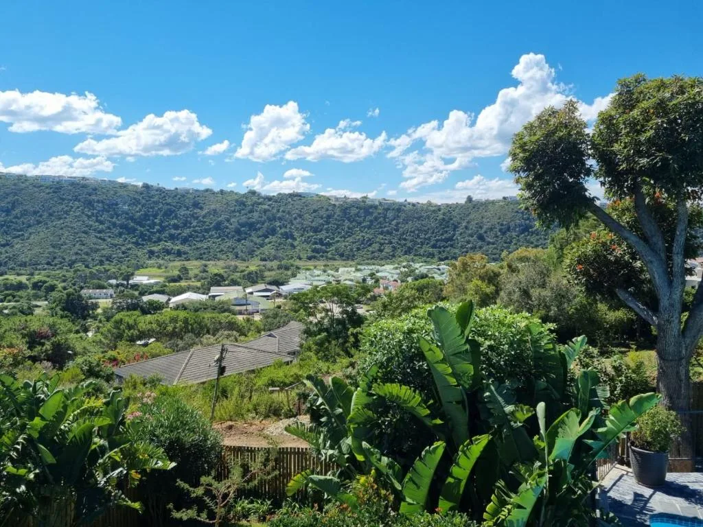 Scenic valley and forested hills stretching toward distant mountains under blue sky