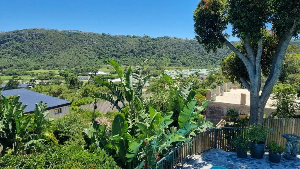 Scenic valley view with river, green hills, and coastal town in distance