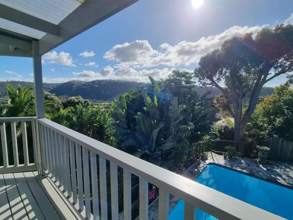 Scenic valley and mountains visible beyond lush garden with pool below