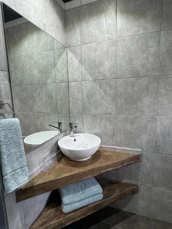 Modern bathroom with round white basin sink on wooden vanity