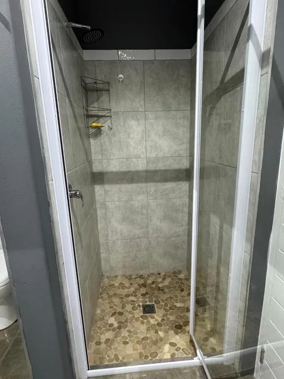 Modern walk-in shower with grey tile walls and pebble floor