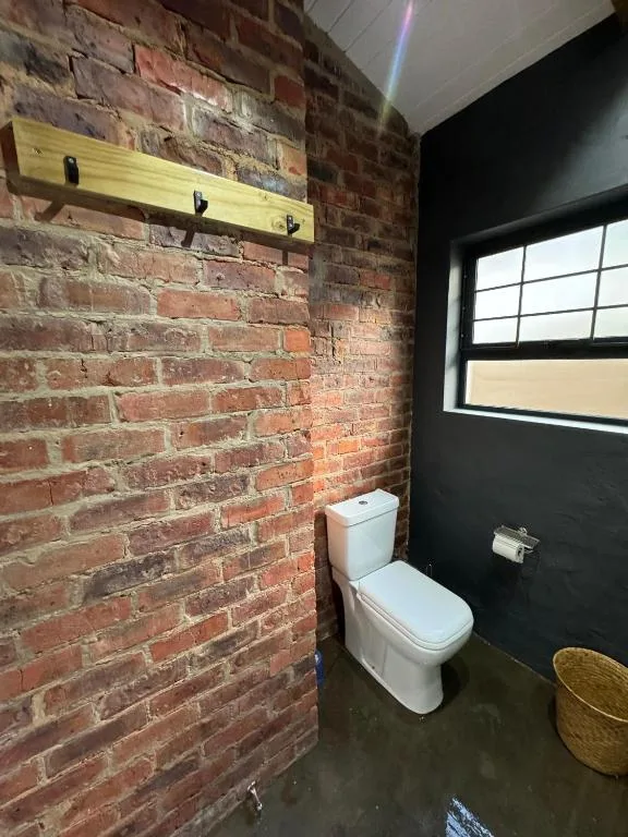 Modern bathroom with exposed brick wall, white toilet, and large window