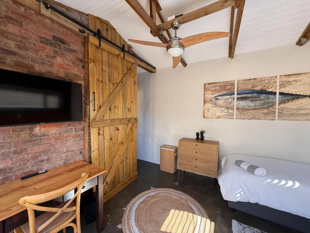 Rustic bedroom with queen bed, wooden desk, and exposed beam ceiling