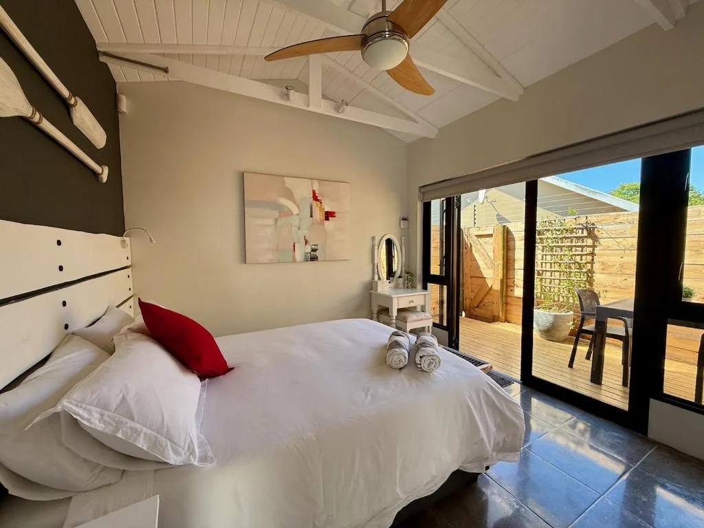 Bright bedroom with queen bed, red accent pillow, and sliding glass doors to deck