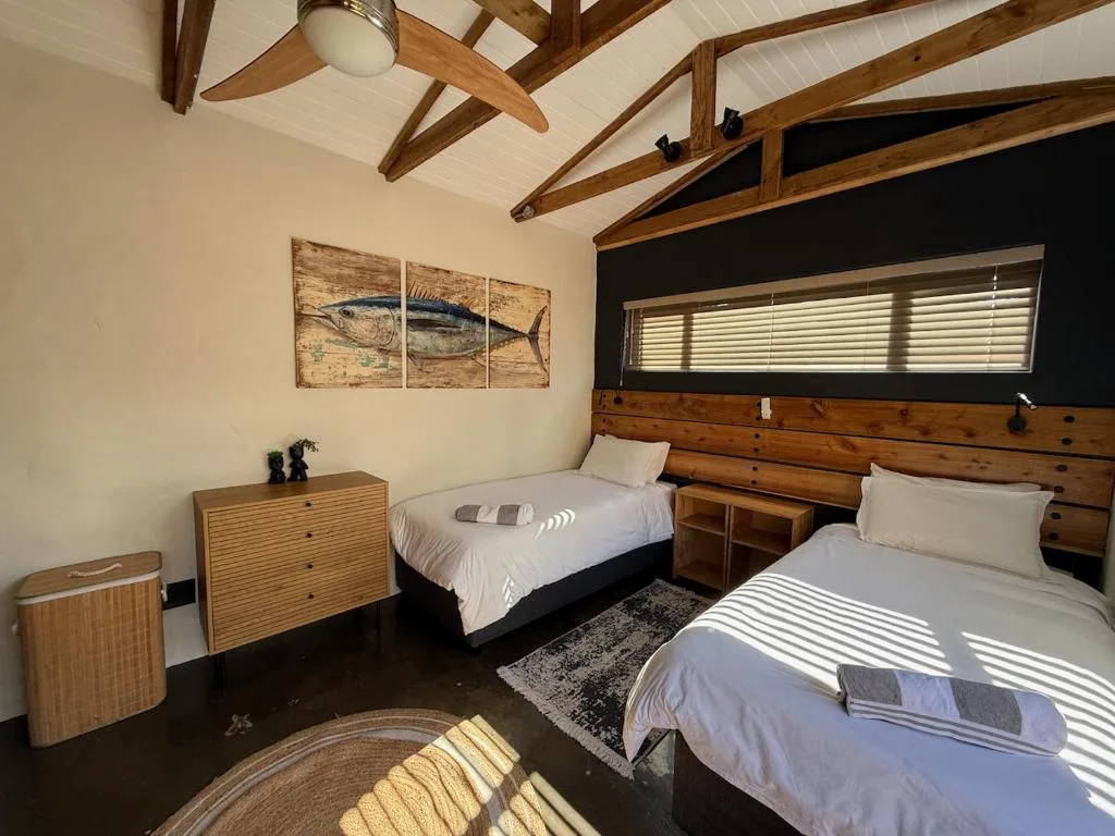 Spacious bedroom with two beds, wooden beams, and fish artwork on walls