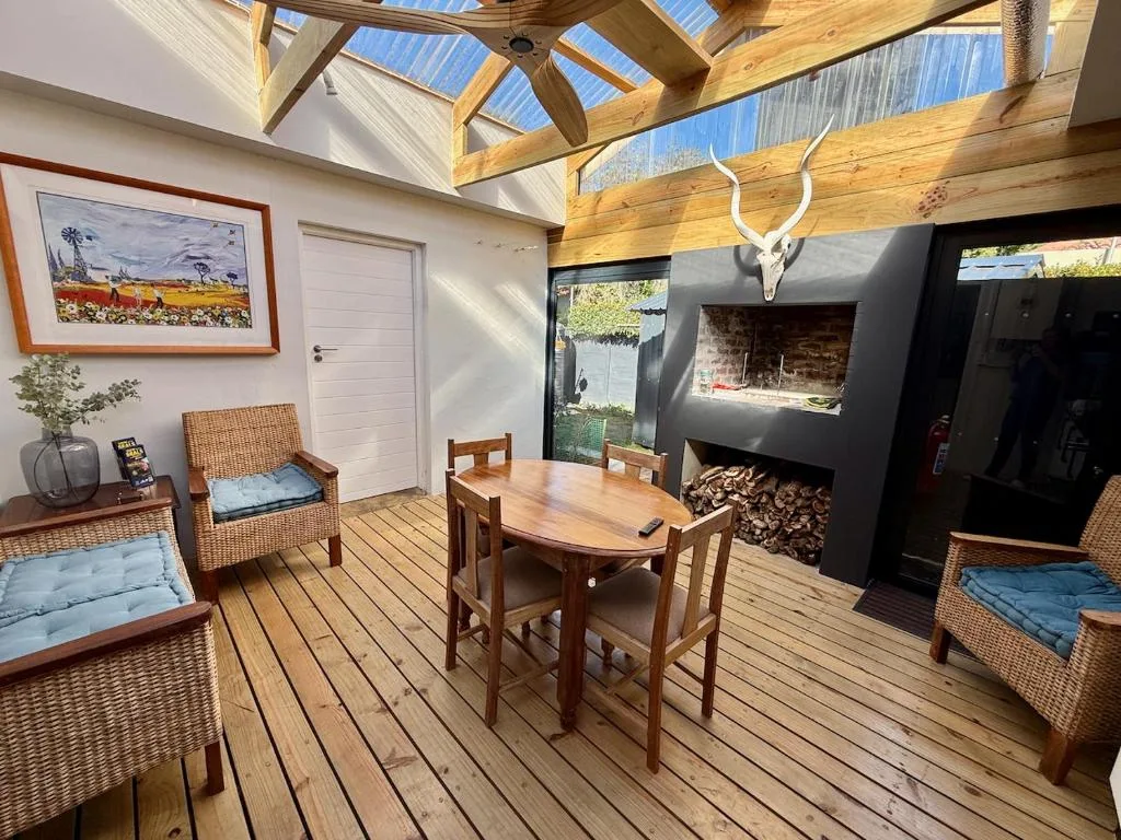 Wooden deck with dining table, wicker seating, and fireplace