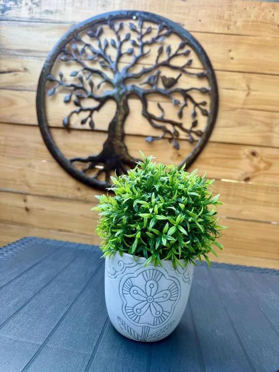 Decorative potted plant with tree-of-life wall art on wooden floor