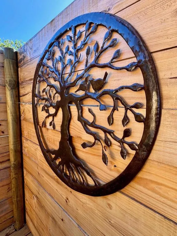 Decorative metal tree artwork mounted on wooden exterior wall