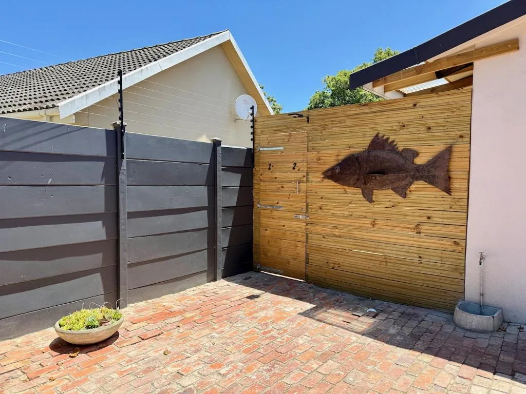 Modern home exterior with wooden gates and brick driveway entrance