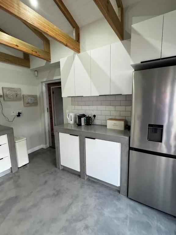 Modern kitchen with stainless steel fridge, white cabinetry, exposed wooden beams