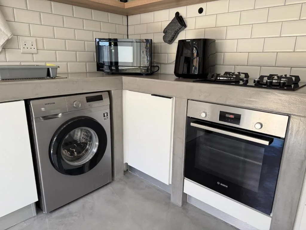 Modern kitchen with washing machine, oven, microwave, and coffee maker appliances