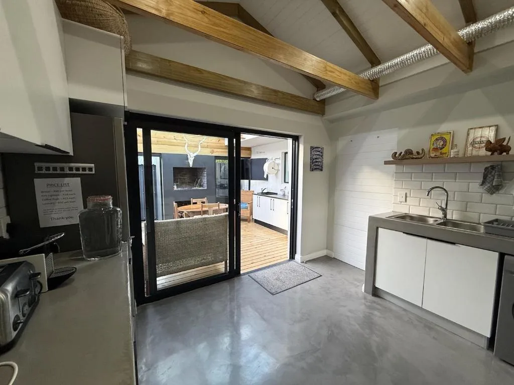 Modern kitchen with white cabinetry, stainless steel sink, and wooden beam ceiling