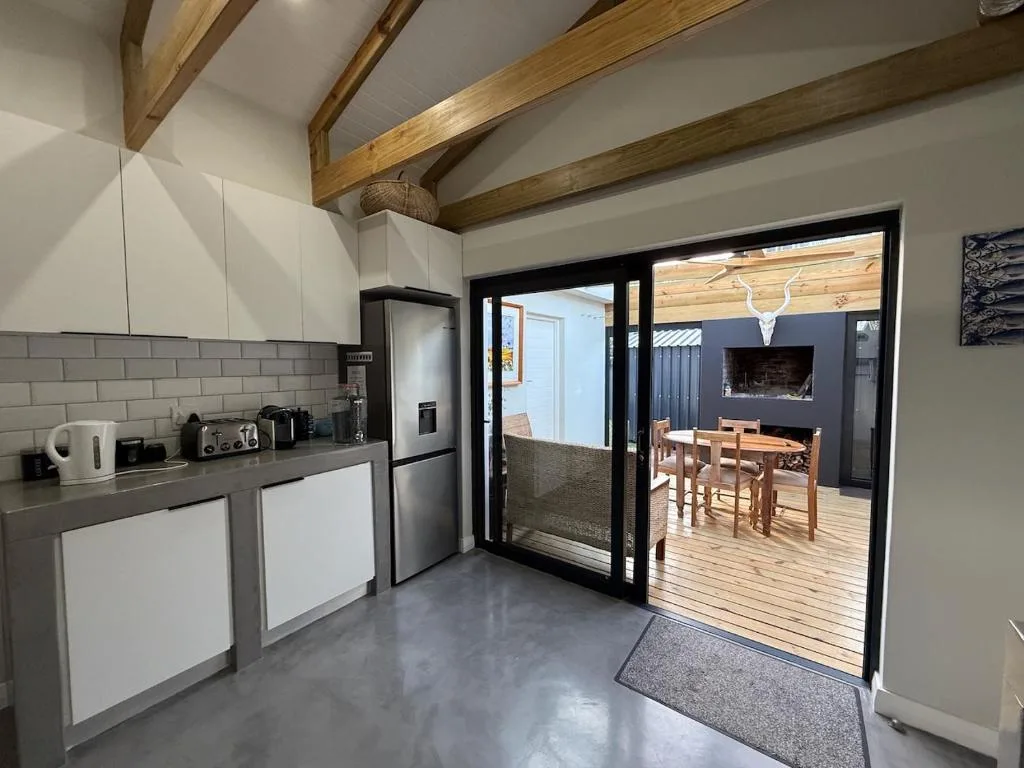 Modern kitchen with white cabinetry, stainless steel appliances, exposed wooden beams