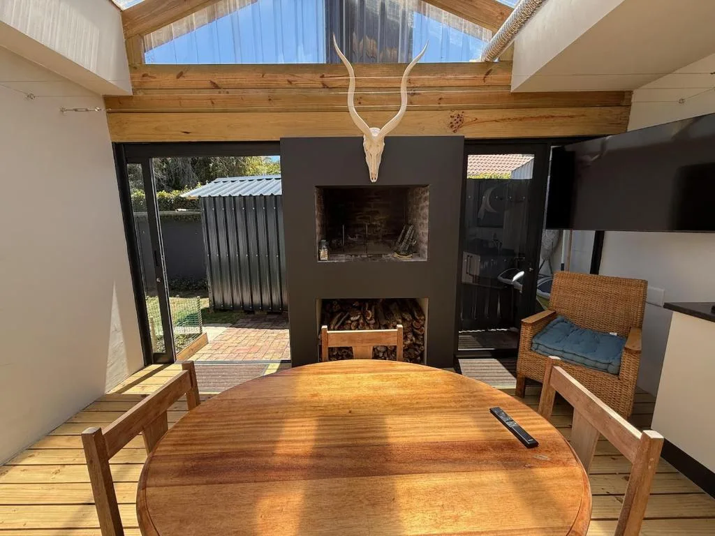 Open-plan lounge with fireplace, wooden beams, and skylights above