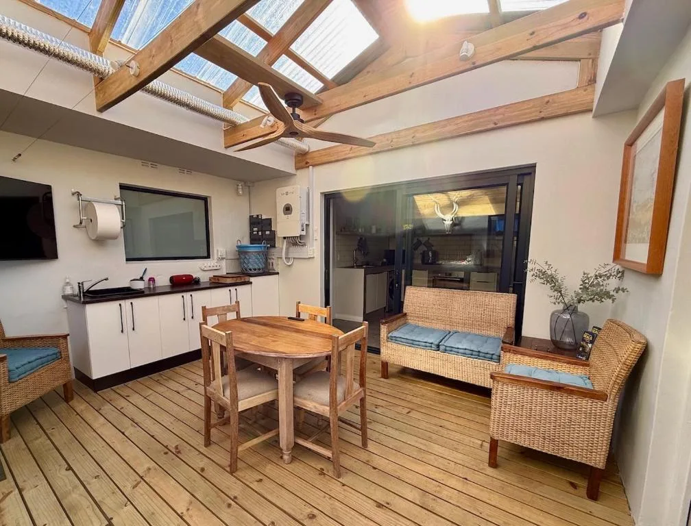 Open-plan lounge and kitchen with wooden beams, rattan seating, and skylights