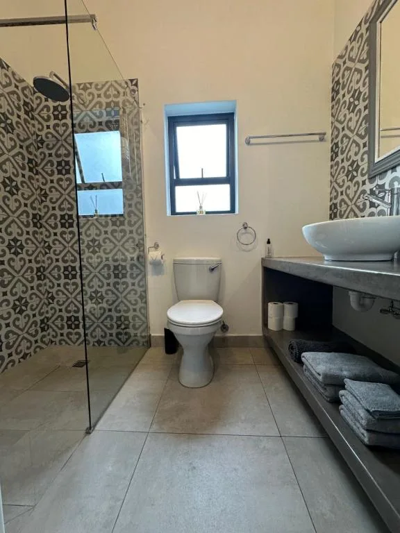Modern bathroom with walk-in shower, vessel sink, and patterned tilework
