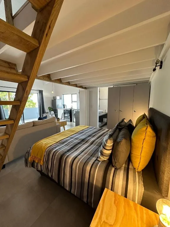 Modern bedroom with striped bedding, exposed wooden beams, and large windows