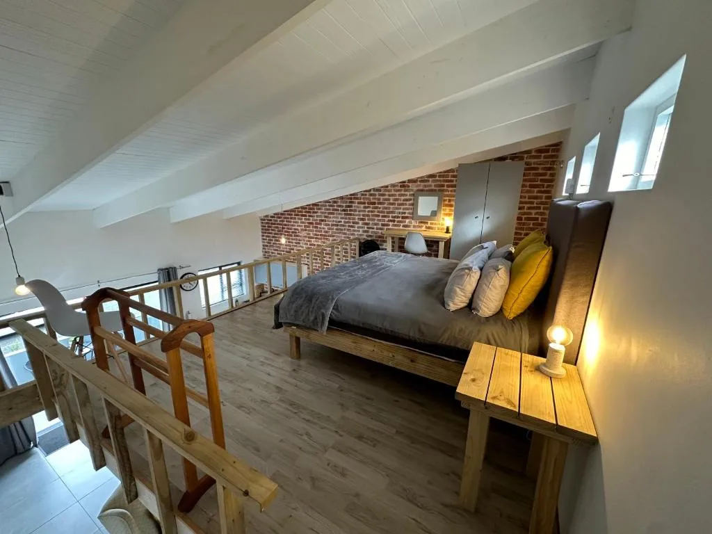 Spacious loft bedroom with exposed brick, queen bed, and skylights