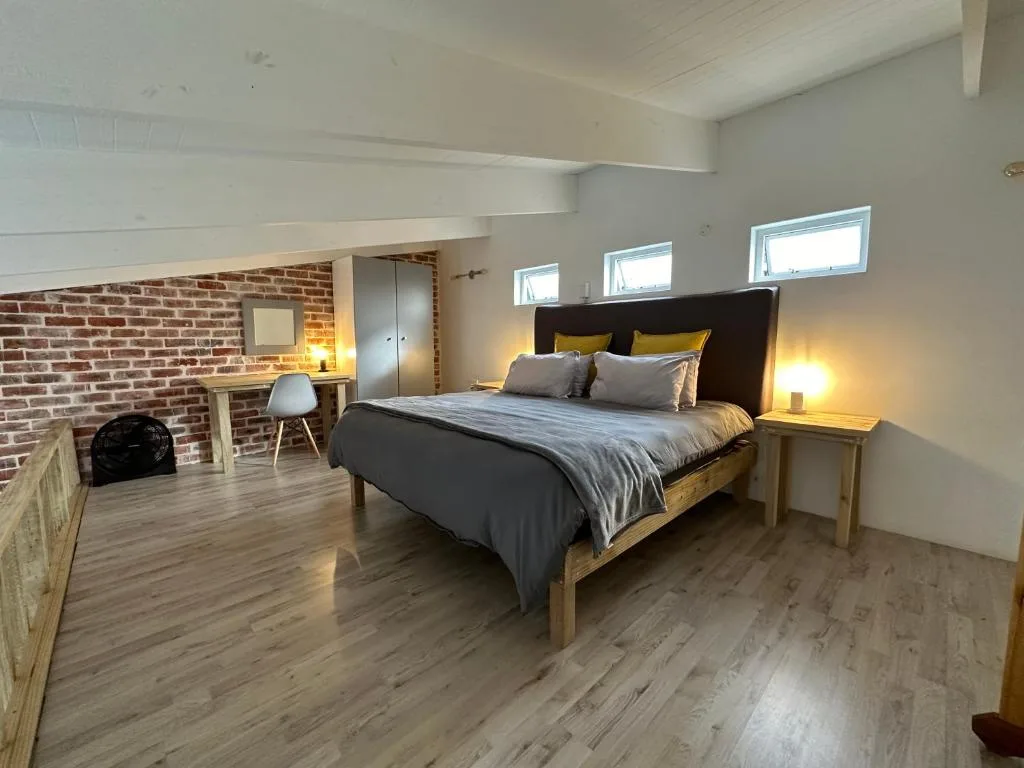 Spacious modern bedroom with wooden bed frame and brick accent wall
