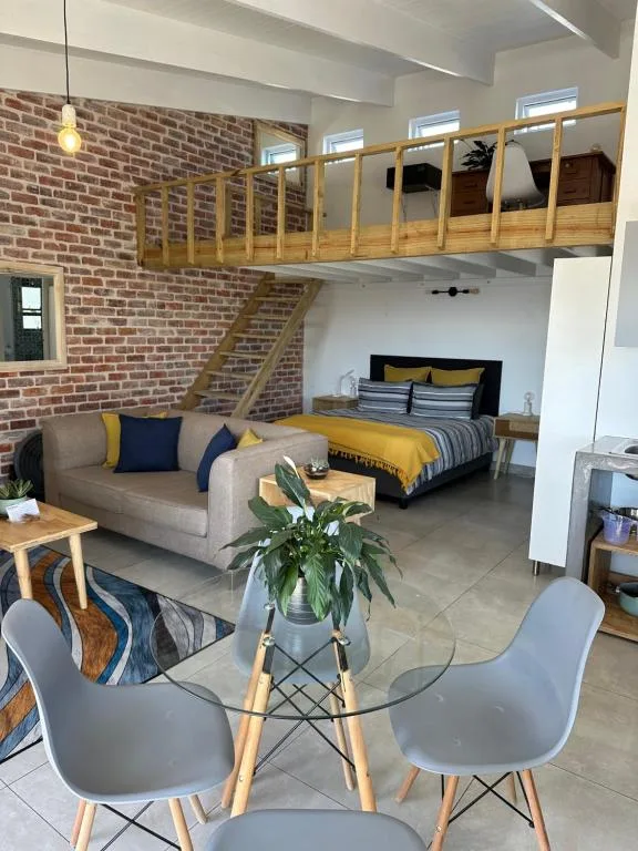 Modern loft bedroom with mezzanine, exposed brick, and contemporary furnishings