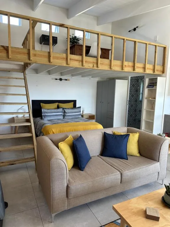 Modern bedroom with loft bed, sofa seating, and yellow accents
