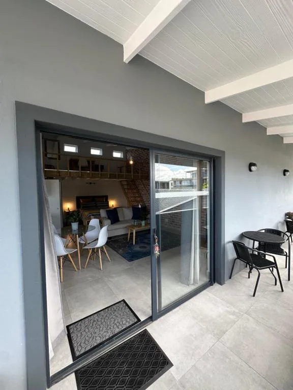 Modern patio area with sliding glass doors opening to furnished lounge space